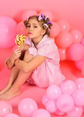 child eat lollipop on pink.