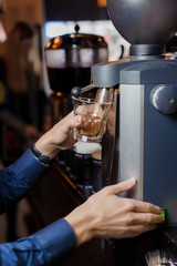 Fototapeta na wymiar the barista's hand pours coffee out of the coffee machine glass beaker