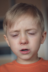 Five years old boy with allergy runny nose and closed eyes.