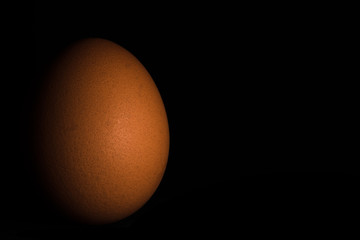 seitlich beleuchtetes Ei vor schwarzem Hintergrund