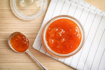 Jar and spoon with sweet jam on wooden table