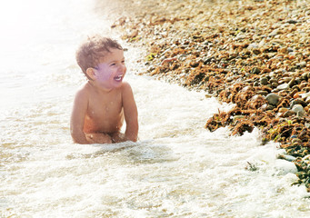 Nine month old baby boy sitting on the beach in beautiful summer day