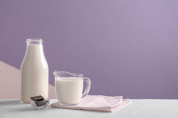 Composition with milk and chocolate on table against color background