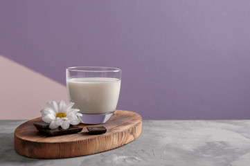 Obraz na płótnie Canvas Glass of milk and chocolate on table against color background