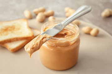 Jar and knife with creamy peanut butter on table