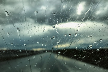 Rain drops on a car windshield. Rainy day view through a car window. Rainy season concept