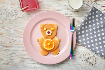 Flat lay composition with pancakes in form of bear on wooden background. Creative breakfast ideas for kids