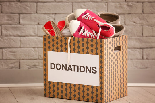 Donation box with shoes on floor against brick wall
