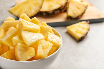 Bowl with fresh pineapple slices on grey background, closeup