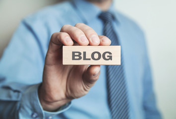 Businessman showing Blog word in wooden block.