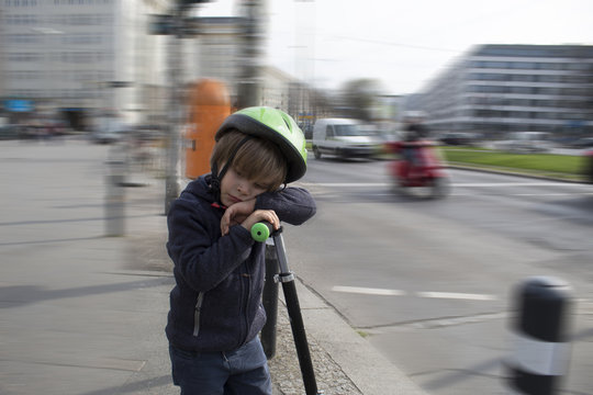 Niño con casco apoyado en su patinete. Alemania. Berlín