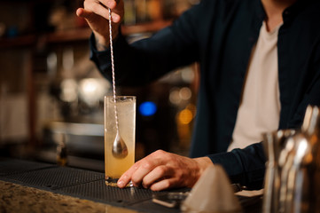Fototapeta na wymiar Barman hand stirring a fresh and sweet orange summer cocktail
