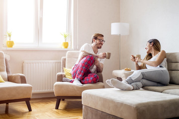 Cheerful young couple drinking morning coffee together at home