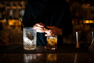 Jar of ice and a glass filled with a fresh summer cocktail on the bar counter