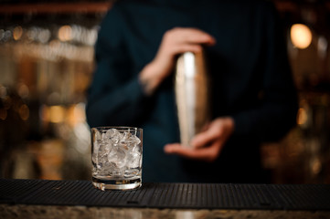 Transparent cocktail glass filled with ice cubes on the bar