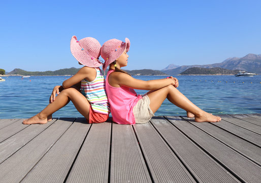 little girls sitting on the beach and sunbathe in the sun