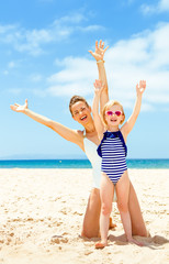 happy young mother and daughter on seashore rejoicing