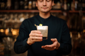 Bartender serving a fresh cocktail with a cucumber at bar counter