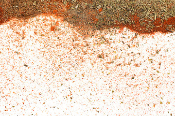 Different spices and herbs scattered on white