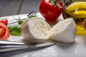 Traditional italian food - white ball mozzarella buffalo Italian soft cheese with cheese knife, tomato, basil, olive oil