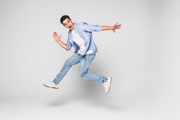 Fototapeta na wymiar Smiling joyful man jumping on white background.