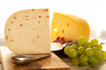Dutch hard cheese Maasdam or Emmentaler, cheese with holes and white hard goat cheese with coriander