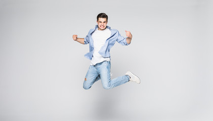 Full-length photo of funny man in casual t-shirt and jeans running or jumping in air isolated over...