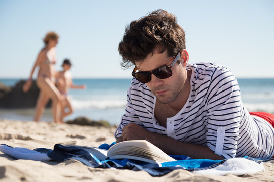 Smart handsome man reading a book on beach holiday