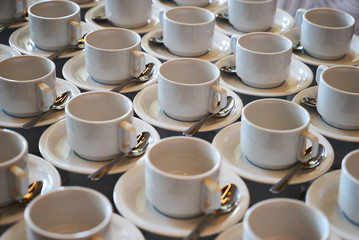 Set of Empty white ceramic tea or coffee cup and saucers. Group of empty cups stacked in rows for serving coffee in restaurant
