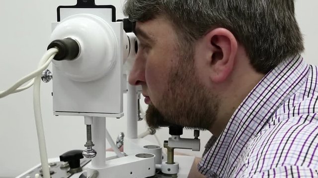 Patient in ophthalmology clinic. Man looks in synoptophore - ophthalmic instrument, used for diagnosing imbalance of eye muscles and treating them by orthoptic methods, for treatment of strabismus