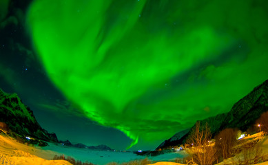 Northern lights shine bright and beautiful above sharp peaks and lakes of Lofoten mountains