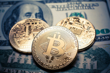 Bitcoin. Gold Bitcoins on a one hundred dollar bill close up
