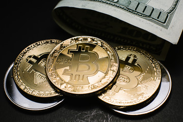Bitcoin. Gold Bitcoins on a one hundred dollar bill close up
