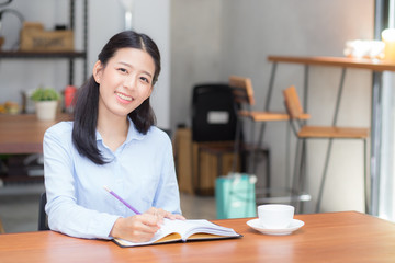 Beautiful business asian young woman writing on notebook on table, girl work at coffee shop, freelance business concept.