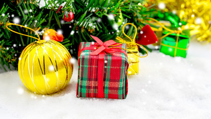 Christmas background with a red ornament, golden gift box in snow