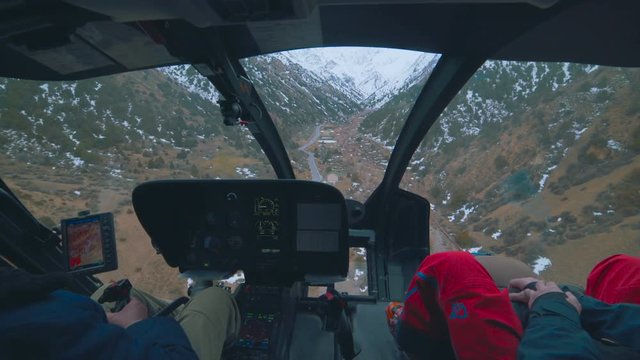 View from the inside of a helicopter approaching over mountains