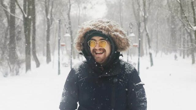 happy laughing handsome man enjoying winter snowfall and looking at camera joyful emotional face outside portrait stylish cheerful smiling guy businessman flying snowflakes peaceful cute good mood