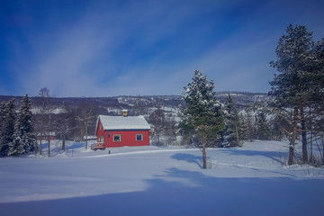 Outdoor view of red wooden typical housecovered with snow in the roof in GOL