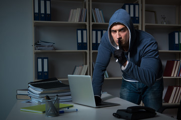 Young hacker hacking into computer at night