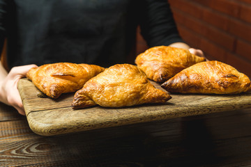 Uzbek national dish of samsa on a wooden board in the hands of a girl