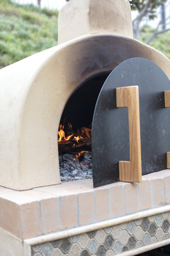 Pizza oven made of brick, cement and tile being prepped for baking pizza with firewood