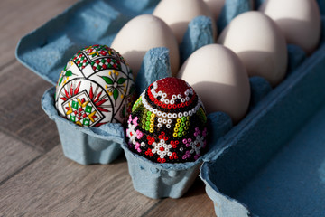 white organic eggs in tray and traditional painted easter eggs from Bucovina region, Romania
