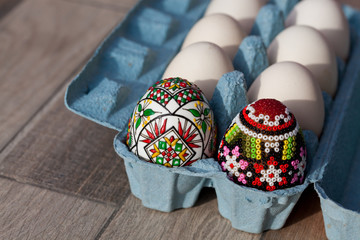 white organic eggs in tray and traditional painted easter eggs from Bucovina region, Romania