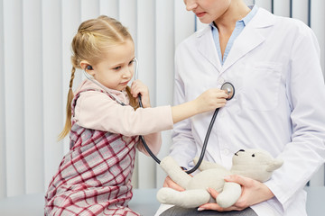 Little girl listening to doctor's heart beat with stethoscope