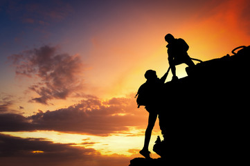 Silhouette of tourists man pulled up woman to the mountain