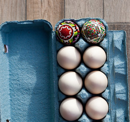 white organic eggs in tray and traditional painted easter eggs from Bucovina region, Romania