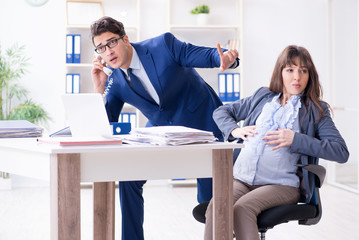 Pregnant woman struggling in the office and getting colleague he