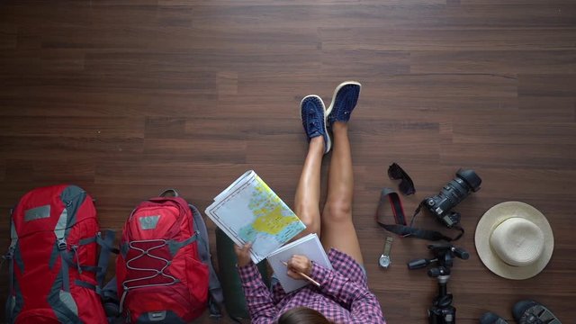 Overhead view of traveler woman plan and backpack travel planning vacation trip. Top view slow motion 