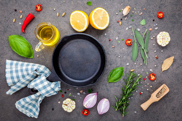 Empty old cast iron skille on dark stone background. Ingredients for making steak  concept with copy space . Various herbs and seasoning rosemary ,sage ,bay leaves ,basil ,garlic and peppercorn.