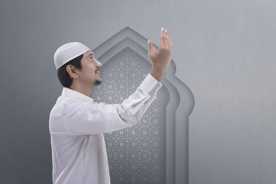 Handsome asian muslim man raising hand and pray